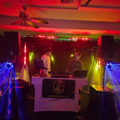 DJ-Setup mit bunten Lichtern und Lautsprechern in einem festlichen Raum.